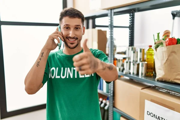 Joven Hombre Hispano Vistiendo Camiseta Voluntaria Hablando Por Teléfono Sonriendo — Foto de Stock