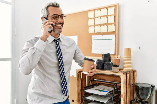 オフィスでスマートフォンのコーヒーを飲む上で話している中年白髪のビジネスマン — ストック写真