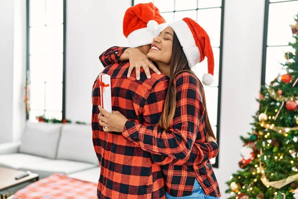 Jovem Casal Latino Sorrindo Feliz Abraçando Segurando Presente Natal Casa — Fotografia de Stock