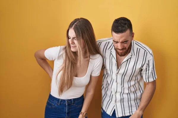 Young Couple Standing Yellow Background Suffering Backache Touching Back Hand — Stock Photo, Image