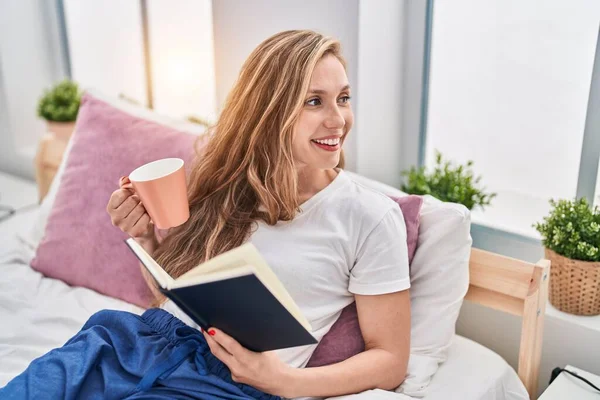 Joven Mujer Rubia Bebiendo Taza Café Libro Lectura Dormitorio — Foto de Stock