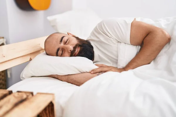 Young bald man lying on bed sleeping at bedroom