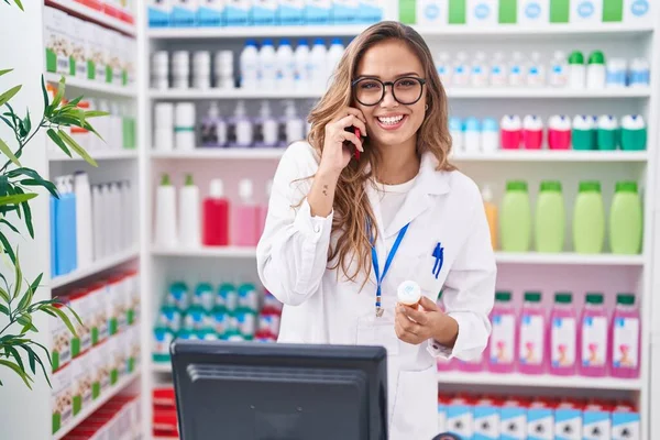 Young Beautiful Hispanic Woman Pharmacist Holding Pills Bottle Talking Smartphone — Stock Photo, Image