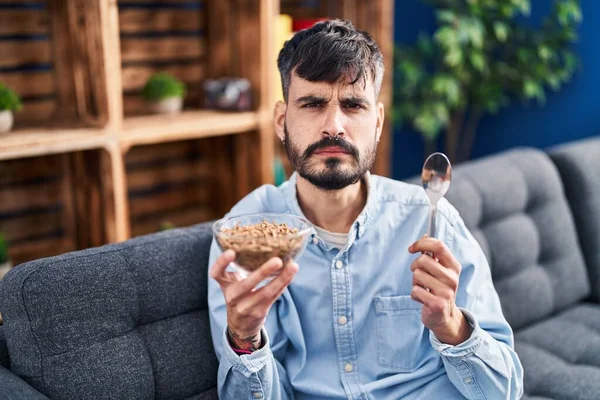 Joven Hombre Hispano Con Barba Comiendo Cereales Integrales Sanos Escéptico — Foto de Stock