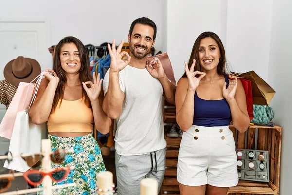 Giysi dükkanında alışveriş torbaları tutan bir grup İspanyol genç parmaklarıyla imza atıp gülümseyerek mükemmel bir sembol oluşturuyorlar. 