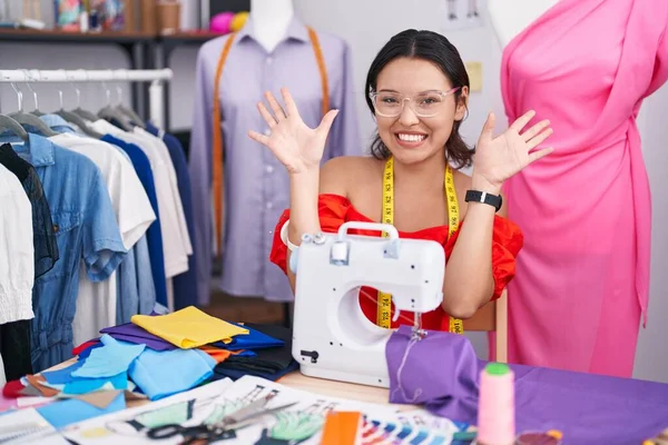 Hispanic Young Woman Dressmaker Designer Using Sewing Machine Showing Pointing — Stockfoto