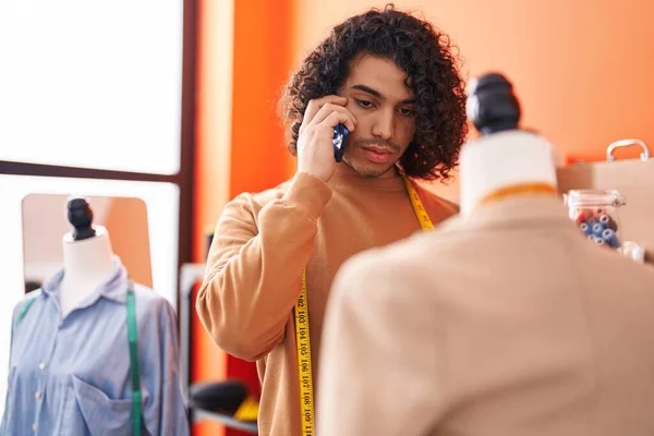 年轻的拉丁男人裁缝师用智能手机在工作室旁边站着 — 图库照片