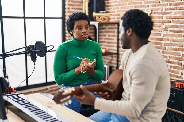 African american man and woman music group compising song at music studio