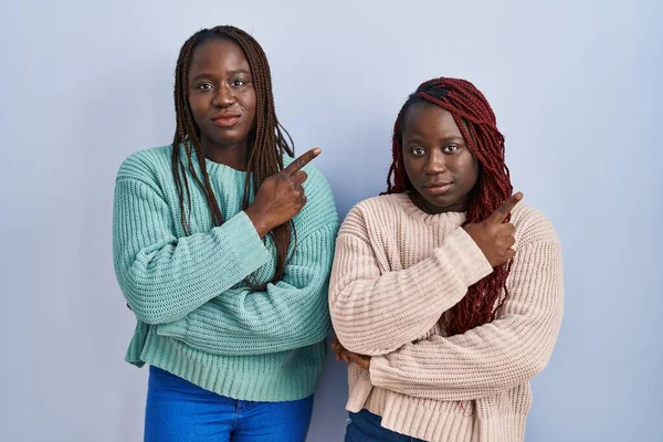 Две Африканки Стоят Синем Фоне Указывая Пальцем Сторону Показывая Рекламу — стоковое фото