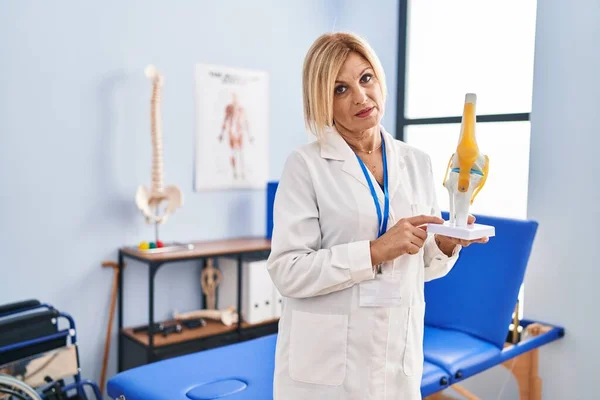 Middle Age Blonde Traumatologist Woman Holding Anatomical Model Knee Joint — Stock fotografie