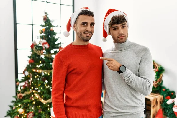 Young Gay Couple Standing Christmas Tree Wearing Hat Pointing Hand — ストック写真