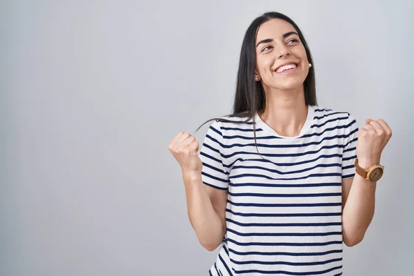 縞模様のTシャツを着た若いブルネットの女性は驚きを祝い 腕を上げて目を閉じて成功に驚いています 勝者のコンセプト — ストック写真