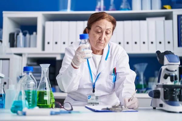 Ανώτερη Γυναίκα Επιστήμονας Μέτρησης Υγρών Γράψει Στο Έγγραφο Στο Εργαστήριο — Φωτογραφία Αρχείου