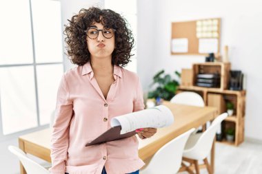 Ofiste iş elbisesi giyen genç bir ortadoğulu kadın komik suratıyla yanaklarını şişiriyor. Havayla şişmiş ağız, çılgın bir ifade.. 