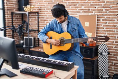 Young arab man musician playing classical guitar at music studio