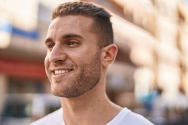 Young caucasian man smiling confident looking to the side at street