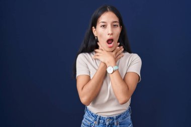 Mavi arka planda dikilen genç İspanyol kadın boğularak öldü diye bağırıyor. Sağlık problemi. Boğulma ve intihar konsepti. 