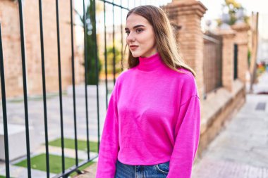 Gülümseyen genç bir kadın sokağın kenarına bakıyor kendinden emin.