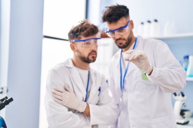 Young couple wearing scientist uniform holding sample at laboratory