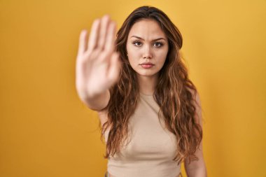 Sarı arka planda duran genç İspanyol kadın avucunun içi gibi şarkı söylemeyi kesiyor. Yüzünde olumsuz ve ciddi bir jest olan uyarı ifadesi. 