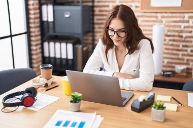 Ofiste çalışan genç bir iş kadını dizüstü bilgisayar kullanıyor.