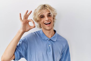 Genç modern adam izole edilmiş arka planda durup gülümsüyor ve el ve parmaklarıyla 