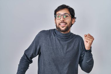 Handsome latin man standing over isolated background dancing happy and cheerful, smiling moving casual and confident listening to music 