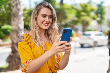 Sokakta akıllı telefon kullanan kendine güvenen genç bir kadın.
