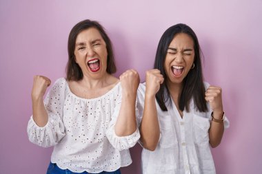 İspanyol anne ve kızı birlikte çok mutlu ve heyecanlı bir şekilde kollarını kaldırıp, gülümseyerek ve başarı için çığlık atarak kazanan jestler yapıyorlar. kutlama konsepti. 