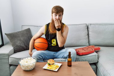 Uzun sakallı, basketbol topu tutan beyaz bir adam TV 'de tezahürat yapıyor, gülüyor ve kıkırdıyor elleri, dedikoduları ve skandalları ağızlarına tıkıyor. 