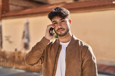 Genç İspanyol adam caddede akıllı telefondan konuşuyor.