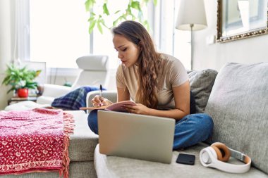 Evdeki kanepede oturan Latin kökenli genç bir kız..