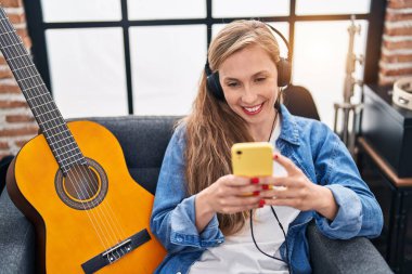 Young blonde woman musician smiling confident listening to music at music studio