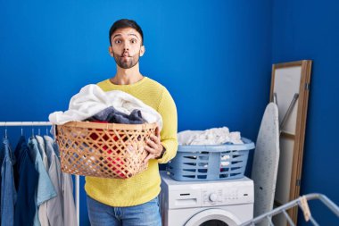 Çamaşır sepetini tutan İspanyol adam ağzıyla balık suratı yapıyor ve şaşı bakıyor, çılgın ve komik.. 