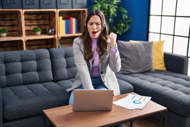 Genç esmer kadın bilgisayar kullanıyor sinirlenmiş ve sinirlenmiş bağırıyor, öfkeyle bağırıyor ve el kaldırıyor. 