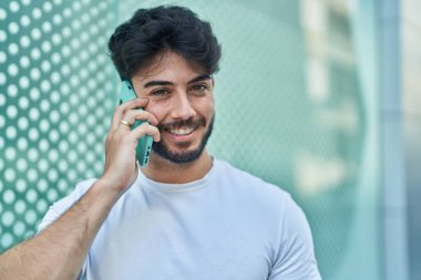 Genç İspanyol adam gülümsüyor. Kendine güveniyor. Sokakta akıllı telefondan konuşuyor.