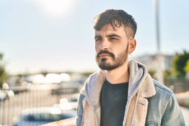 Young hispanic man looking to the side with relaxed expression at street