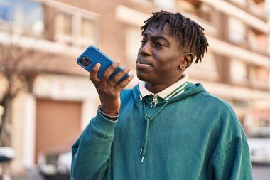 Afro-Amerikalı adam akıllı telefondan konuşuyor. Sokakta ciddi bir ifadeyle.