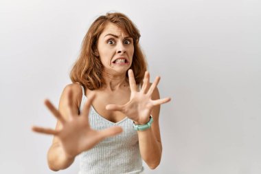 Güzel, beyaz bir kadın izole edilmiş arka planda duruyor korku ifadesinden korkuyor ve dehşete düşüyor. El hareketlerini durdur, şok içinde bağır. panik konsepti. 