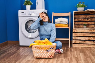 Çamaşır odasında gülümseyen İspanyol bir kadın mutlu bir şekilde el pençe divan duruyor. 