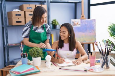 Two women artists using touchpad drawing on notebook at art studio