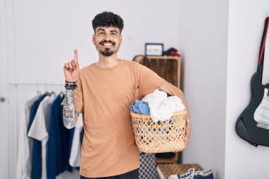 Yatak odasında sakallı, çamaşır sepetini tutan genç İspanyol bir adam bir fikre ya da soru işaretine şaşırdı. 