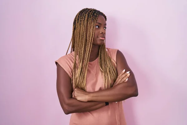 Африканская Американка Плетеными Волосами Стоящая Розовом Фоне Смотрящая Сторону Скрещенными — стоковое фото