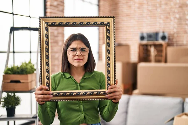 Young Hispanic Woman New Home Holding Empty Frame Skeptic Nervous — Stock Photo, Image