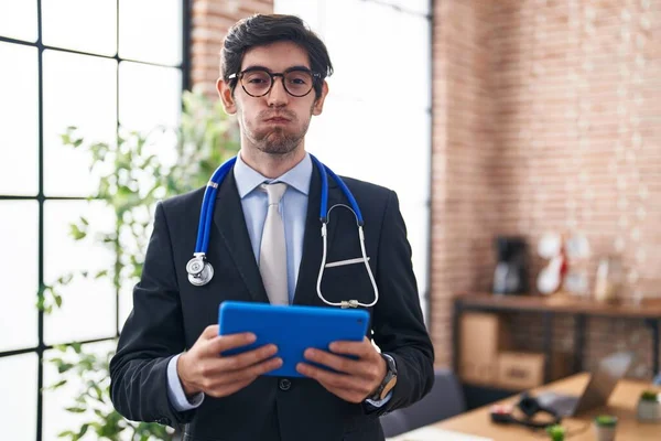 Young Hispanic Man Wearing Doctor Stethoscope Office Puffing Cheeks Funny — Foto de Stock