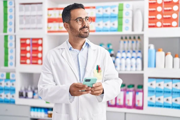 年轻的恐慌男药剂师用智能手机在药店工作 — 图库照片