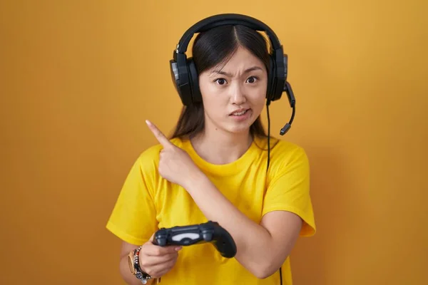 Čínská Mladá Žena Hraje Videohry Držení Ovladač Ukazuje Stranou Ustaraný — Stock fotografie