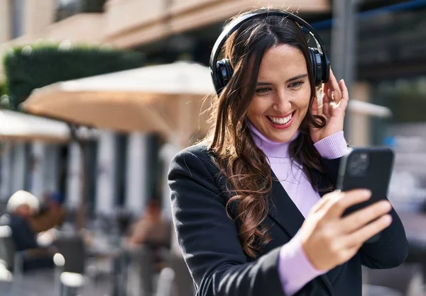 年轻的惊慌失措的女人带着自信的笑容在街上听音乐 — 图库照片