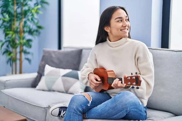 年轻的惊慌失措的女人在家里的沙发上弹奏着四弦琴 — 图库照片