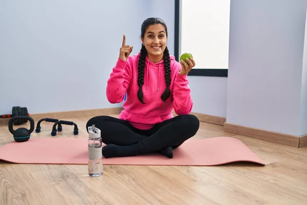 Young Hispanic Woman Sitting Yoga Mat Eating Apple Surprised Idea — Stockfoto